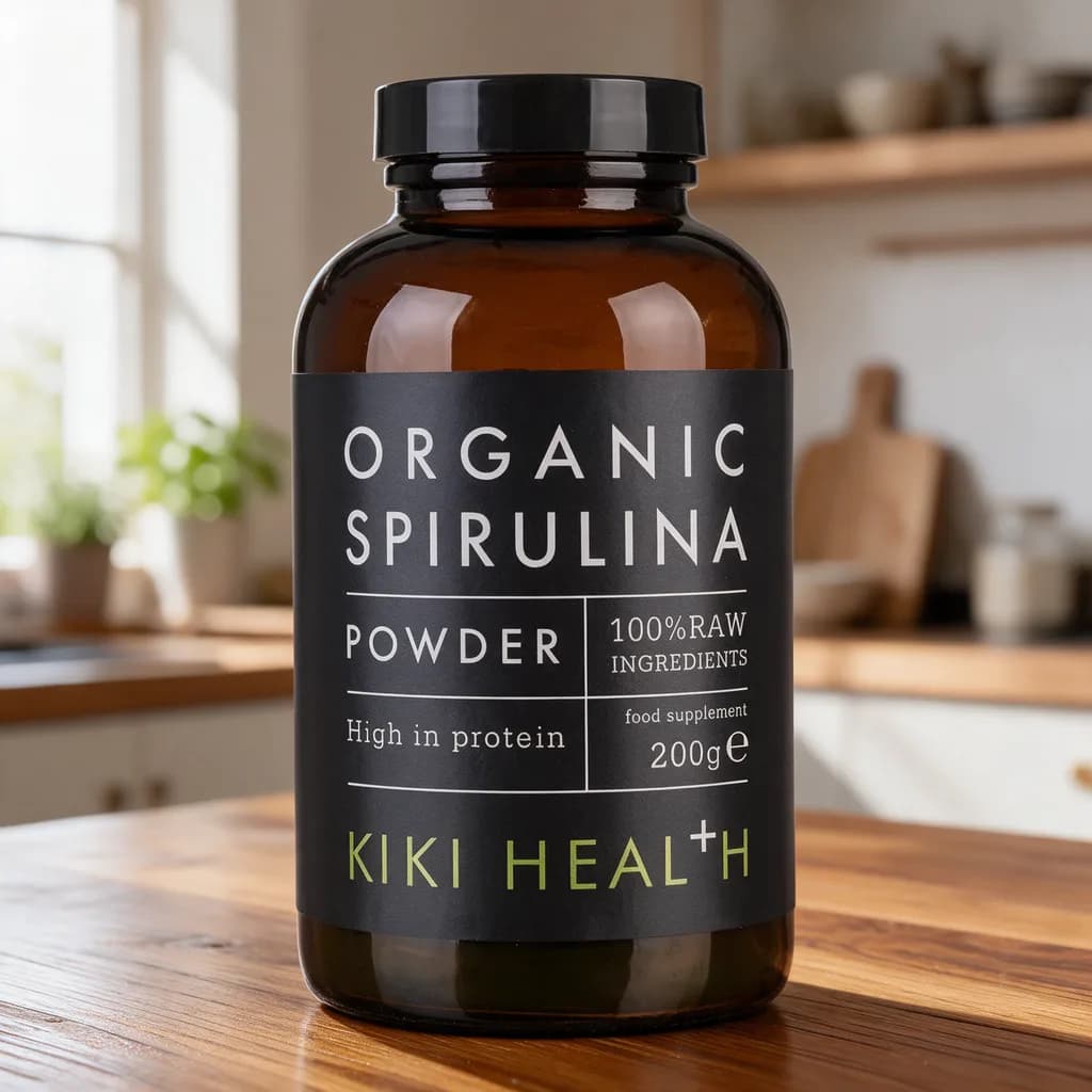 Ruskea Kiki Health Organic Spirulina Powder -lasipurkki mustalla etiketillä puisella keittiön pöydällä